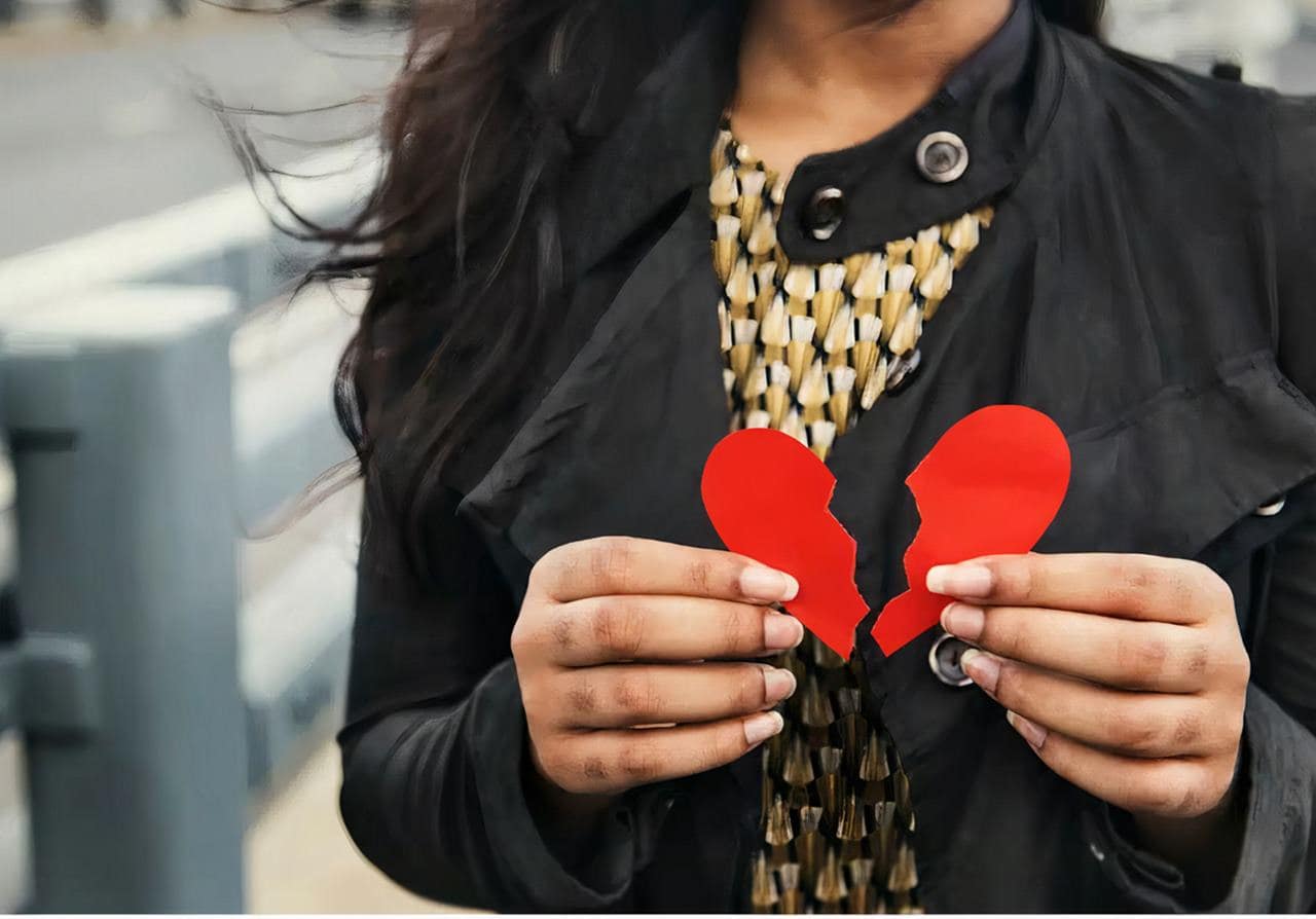 Una donna tiene in mano un cuore spezzato che simboleggia la sua insoddisfazione per la sua relazione attuale.